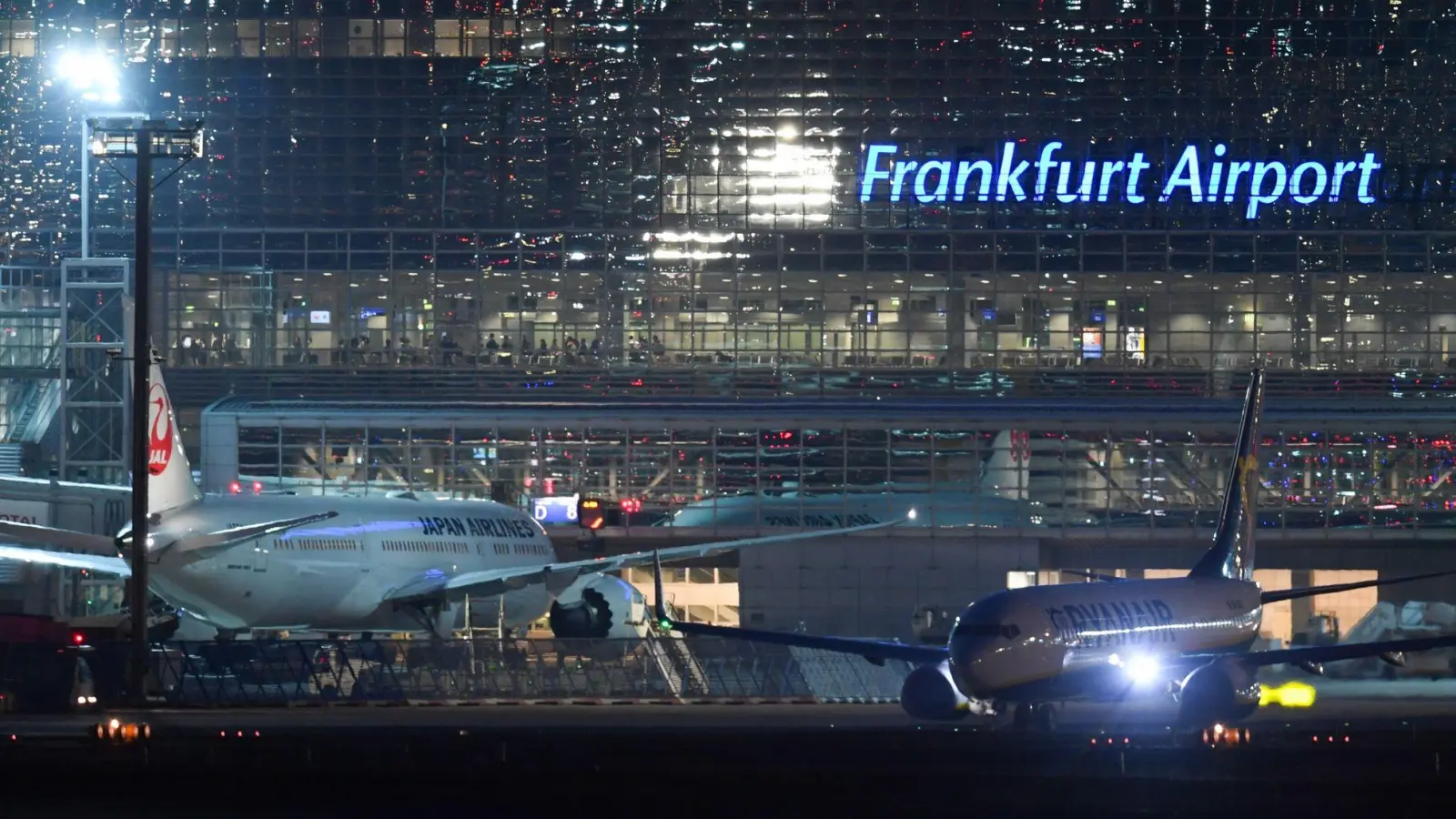 Eine Passagiermaschine der Ryanair (r) rollt nach Sonnenuntergang am Terminal 2 des Frankfurter Flughafens neben einem Flugzeug der Japan Airlines zur Startbahn. Der Flughafen sucht Personal. (Foto: Arne Dedert/dpa)