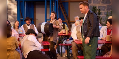 Zünftig geht es im Wirtshaus „Am Wehrgang” zu – eine Szene aus „Kohlhiesls Töchtern” mit Janina Dötterl als Susi, Yannik Dirksen als Toni und Wirtshausgästen. (Foto: Ludwig Olah)