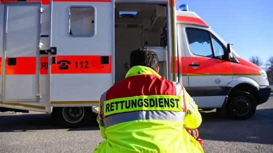 „Rettungsdienst“ steht auf der Jacke eines Mannes vor einem Rettungswagen der Feuerwehr. (Foto: Jens Kalaene/dpa/Symbolbild)