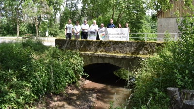 Zum Thema Schwammregion fand ein Pressetermin in Steinbach statt. Die Brücke, auf der die Teilnehmer stehen, wurde beim Starkregen enorm beschädigt, Gebäude standen meterhoch unter Wasser. (Foto: Ute Niephaus)