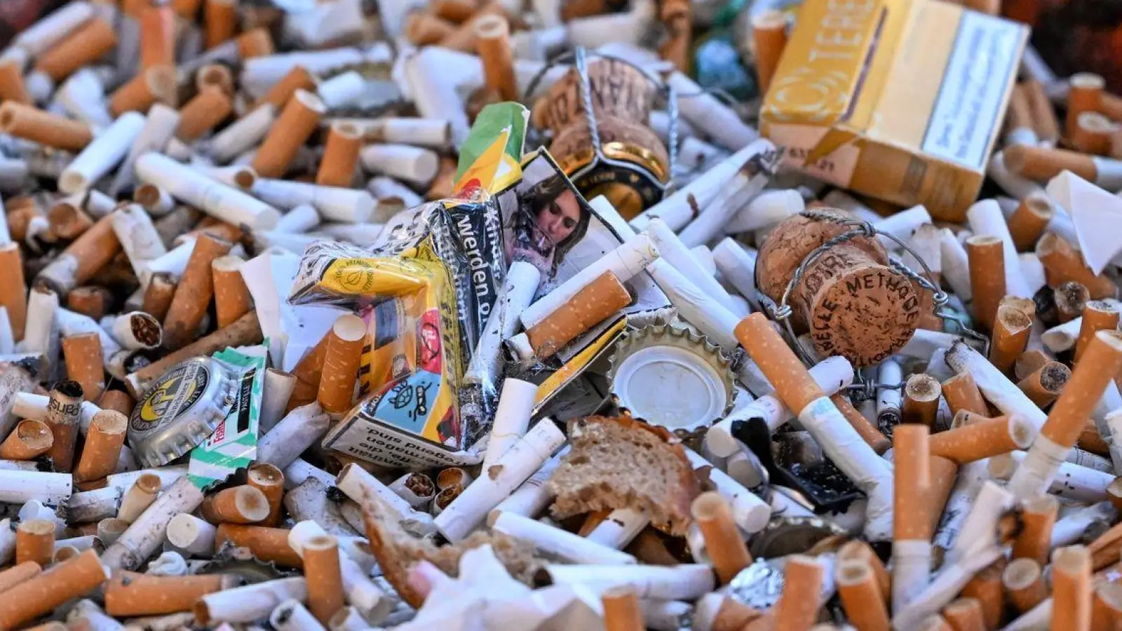 Eine Schale voller Kippen und Zigarettenschachteln. (Foto: Jens Kalaene/dpa)